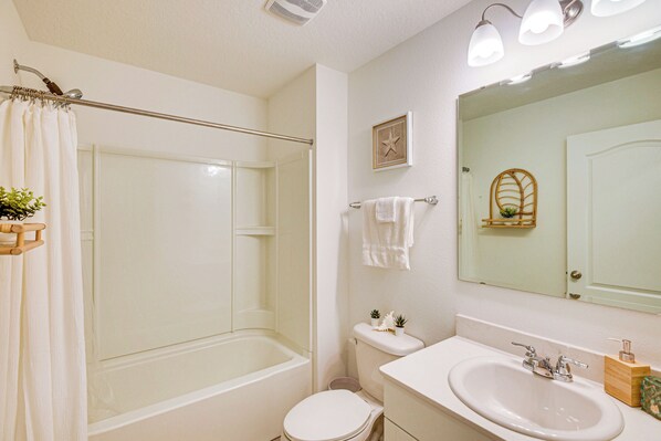 Un baño con bañera, inodoro, lavabo y cortina de ducha.