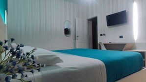 A bedroom with a bed, a bedside table, a TV mounted on the wall, and a ceiling light fixture. - Triple room Tropea center (Tropea)