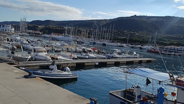A marina with boats docked, a concrete dock, and a mountainous landscape in the background. - Triple room Tropea center (Tropea)