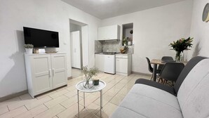 Un espacio habitable compacto con kitchenette, comedor y zona de estar.
