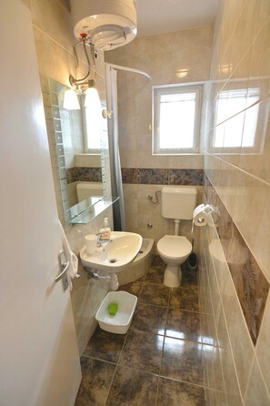 A bathroom with a toilet, sink, and mirror. - Apartmani Vela Makarska (Makarska)