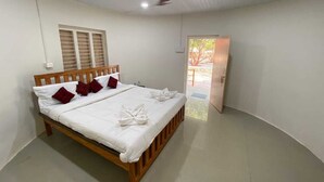Ein sauberes, helles Schlafzimmer mit einem hölzernen Bett, weißen Leinen und einem Deckenventilator.