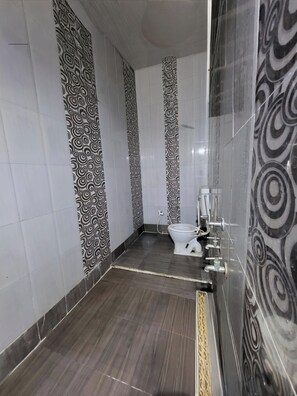 Een badkamer met toilet, wastafel en douche. De muren zijn voorzien van een zwart-wit spiraalpatroon.