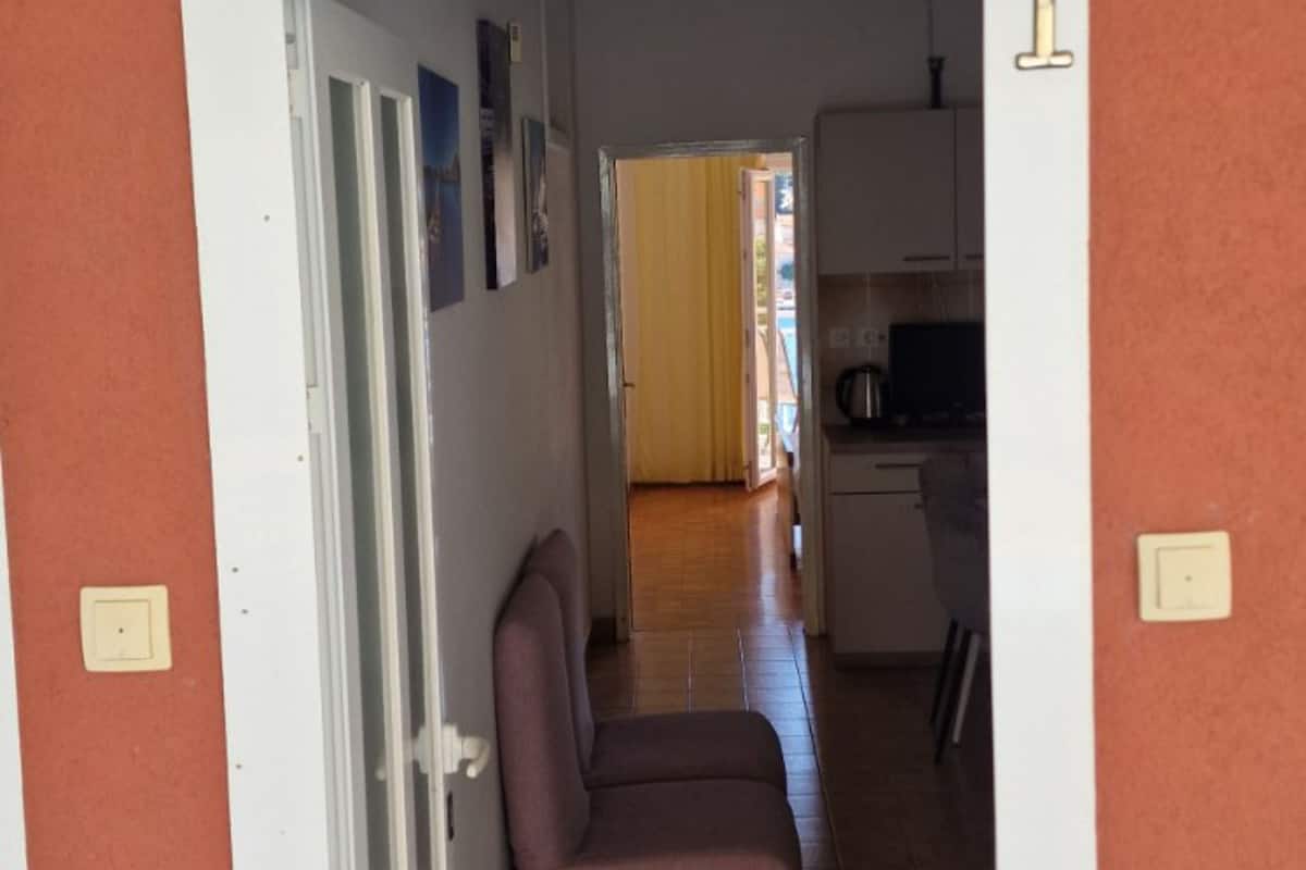 A hallway leading to a kitchen with cabinets and a television.