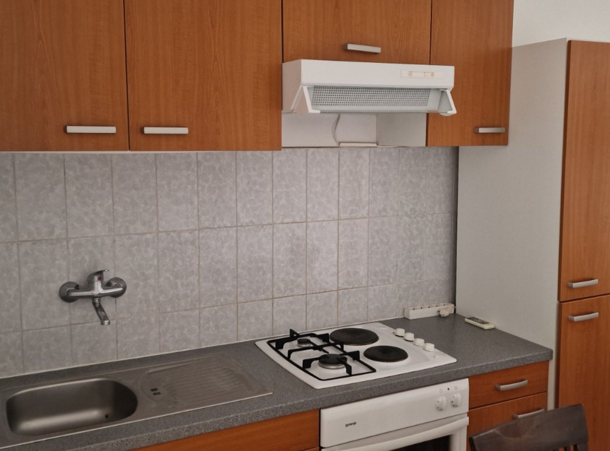 A kitchen with wooden cabinets, a gas stove, a sink, and a white range hood.