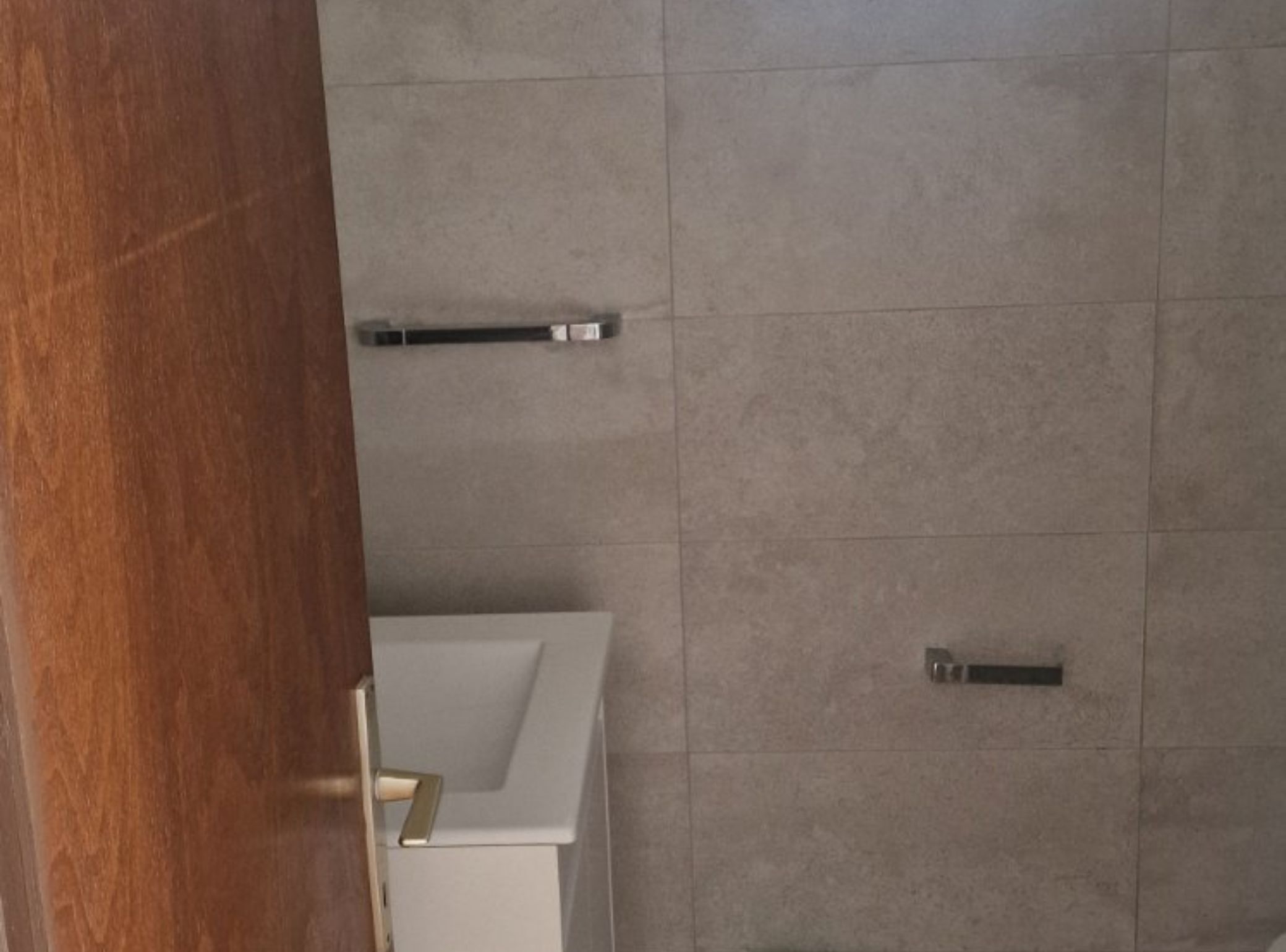 A bathroom with a wooden door, a white sink, and a towel rack on the wall.