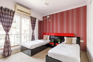 A hotel room with two beds, a red-striped wall, and a large window with curtains. - The Crimson Cove (Bengaluru)