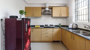 Une cuisine compacte avec des meubles de rangement en bois, une cuisinière à gaz et un four encastré.