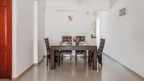 Un coin repas avec une table en verre, des chaises à motifs floraux et un ventilateur de plafond.