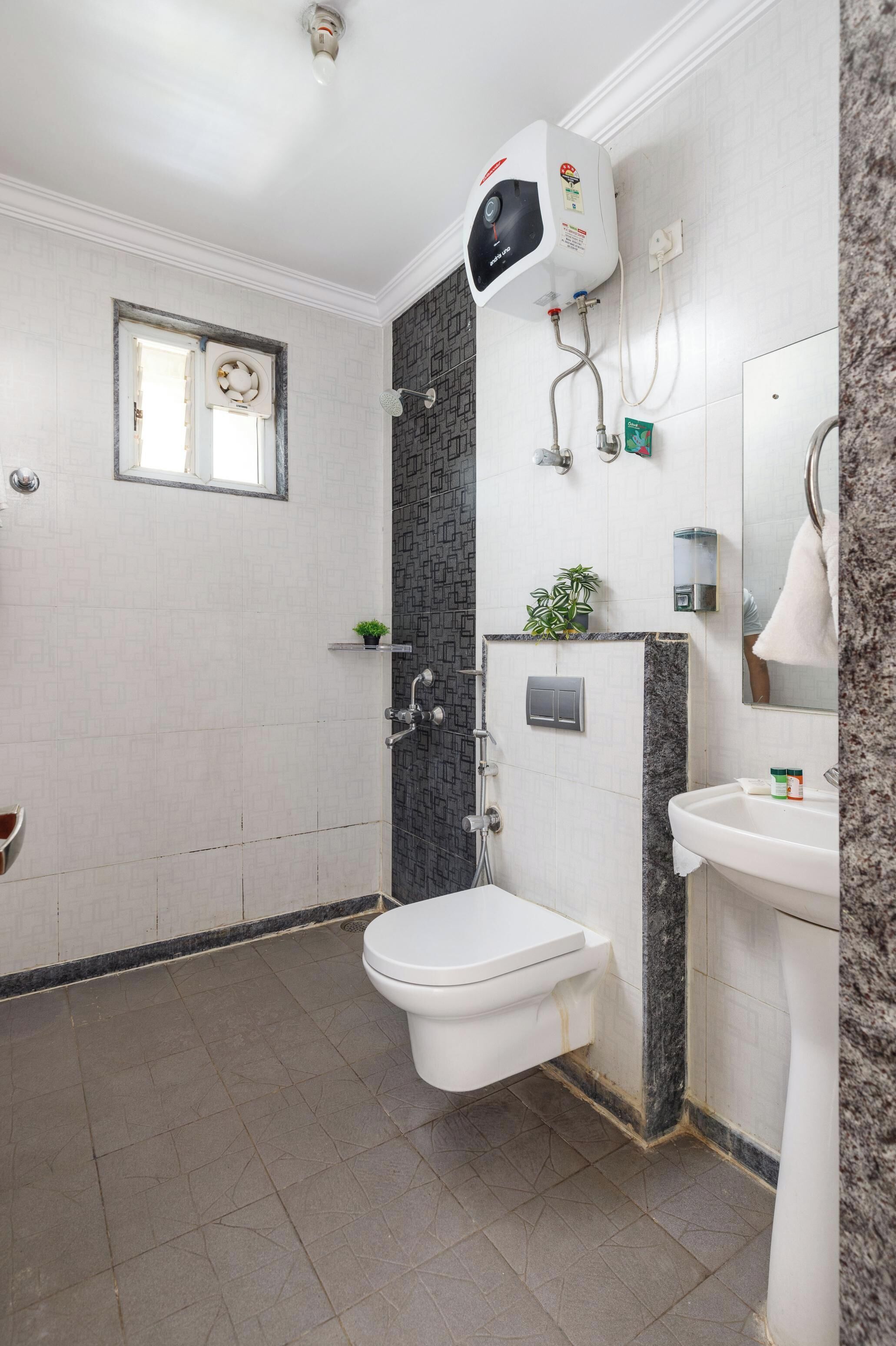 A bathroom with a white toilet, a sink, a shower, and a water heater.