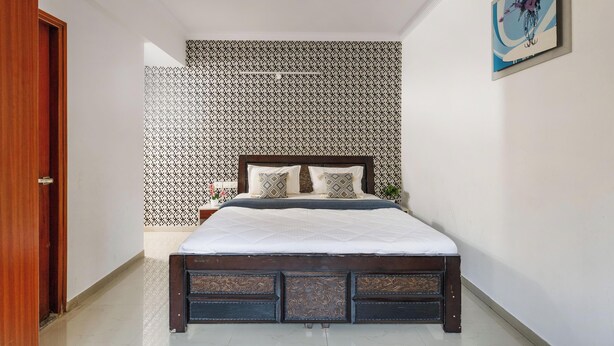 Une chambre à coucher avec un lit, un mur décoré de motifs, un tableau et une porte en bois.