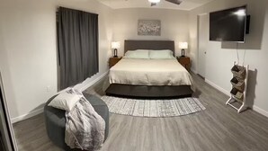 A modern bedroom with a large bed, two bedside tables with lamps, a flat-screen TV mounted on the wall, and a ceiling fan. - Cozy 3BDR/2BATH in N Phoenix. 8mi from Mayo Clinic (Phoenix)