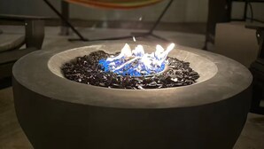 A fire pit with blue flames, surrounded by outdoor furniture, under a covered area with string lights. - Cozy 3BDR/2BATH in N Phoenix. 8mi from Mayo Clinic (Phoenix)