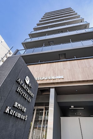 Ein Hotel Eingang mit modernem Design, mit einem gut sichtbaren Schild für 'APARTMENT HOTEL' und der Adresse 'Kuromon 5-5'.