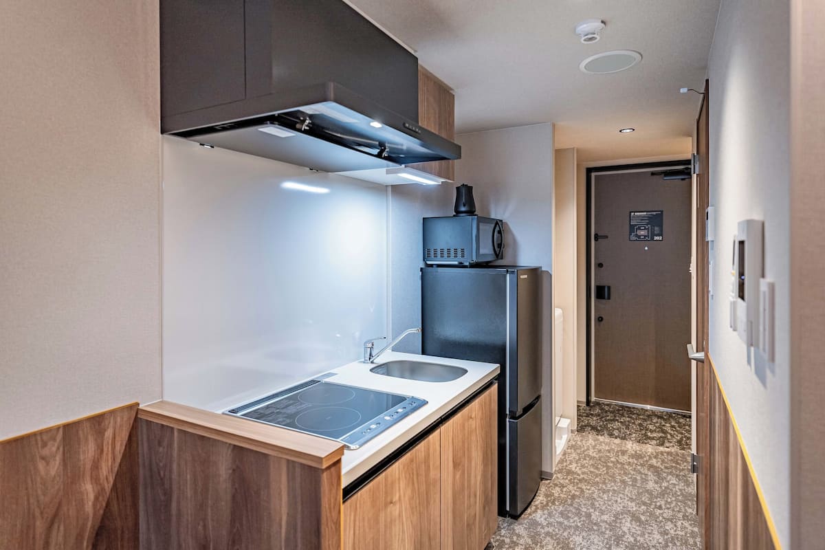 Una cocina compacta con estufa integrada, un lavamanos y un refrigerador negro.
