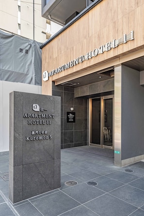 A modern building with a sign for 'APARTMENT HOTEL 11' and a separate sign for 'APARTMENT HOTEL 11 Kuronon 5'. - Apartment Hotel 11 Kuromon 5 (Osaka)
