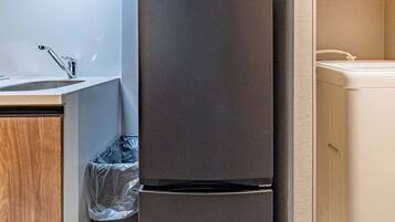 A compact kitchenette with a refrigerator, microwave, and washing machine.