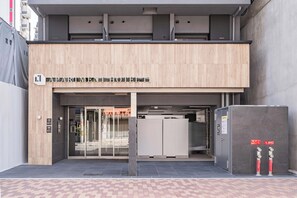 A modern hotel entrance with a sign, glass doors, and a fire safety cabinet.