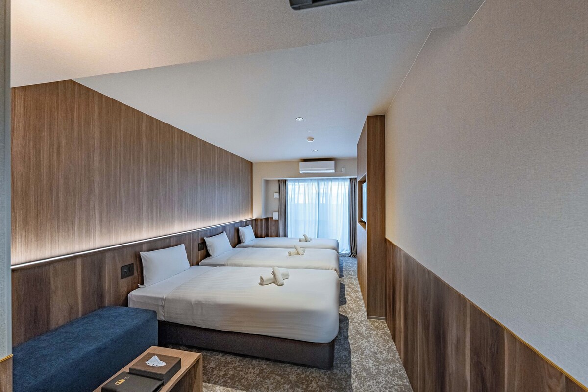 A hotel room with two beds, a sofa, and a small table.
