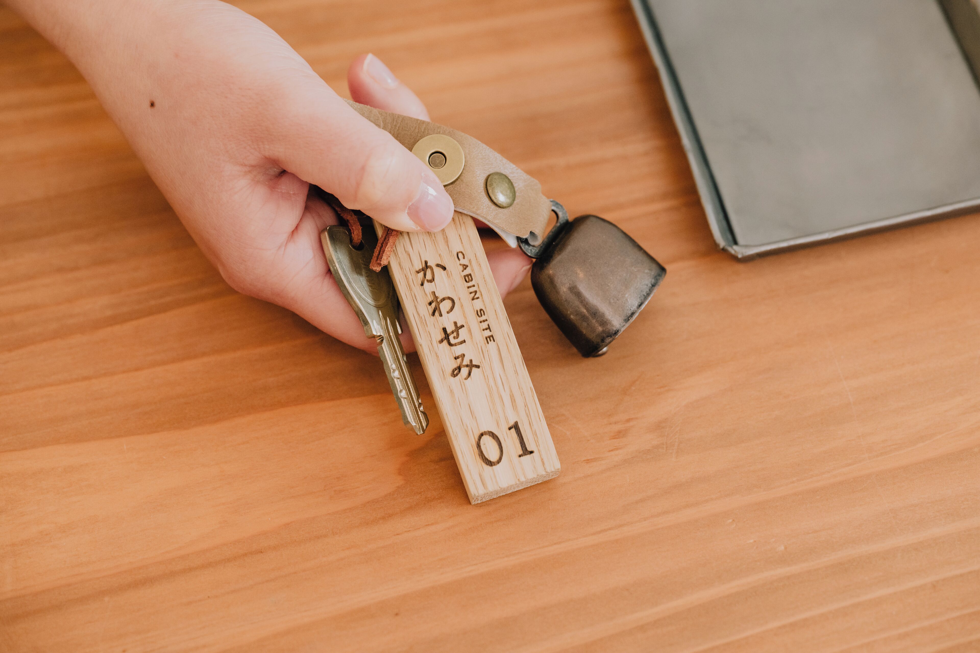 A hand holding a set of keys with a wooden tag labeled "Cabin Site 01".