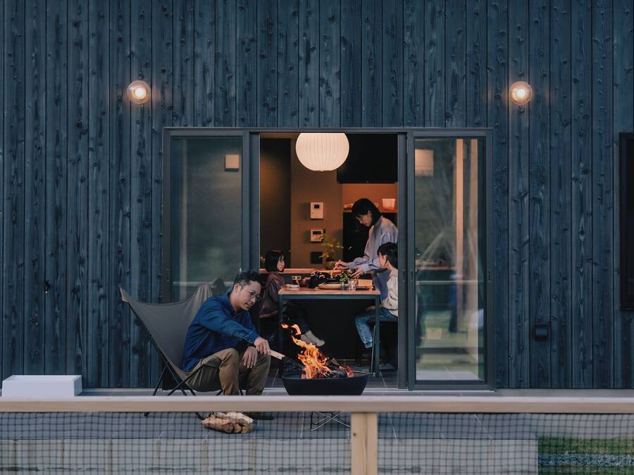 A modern outdoor dining area with a fire pit, a table, and a chair.