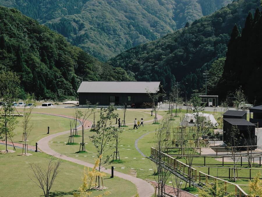 Ein Park mit Wegen, einem Gebäude und einem Berg im Hintergrund.