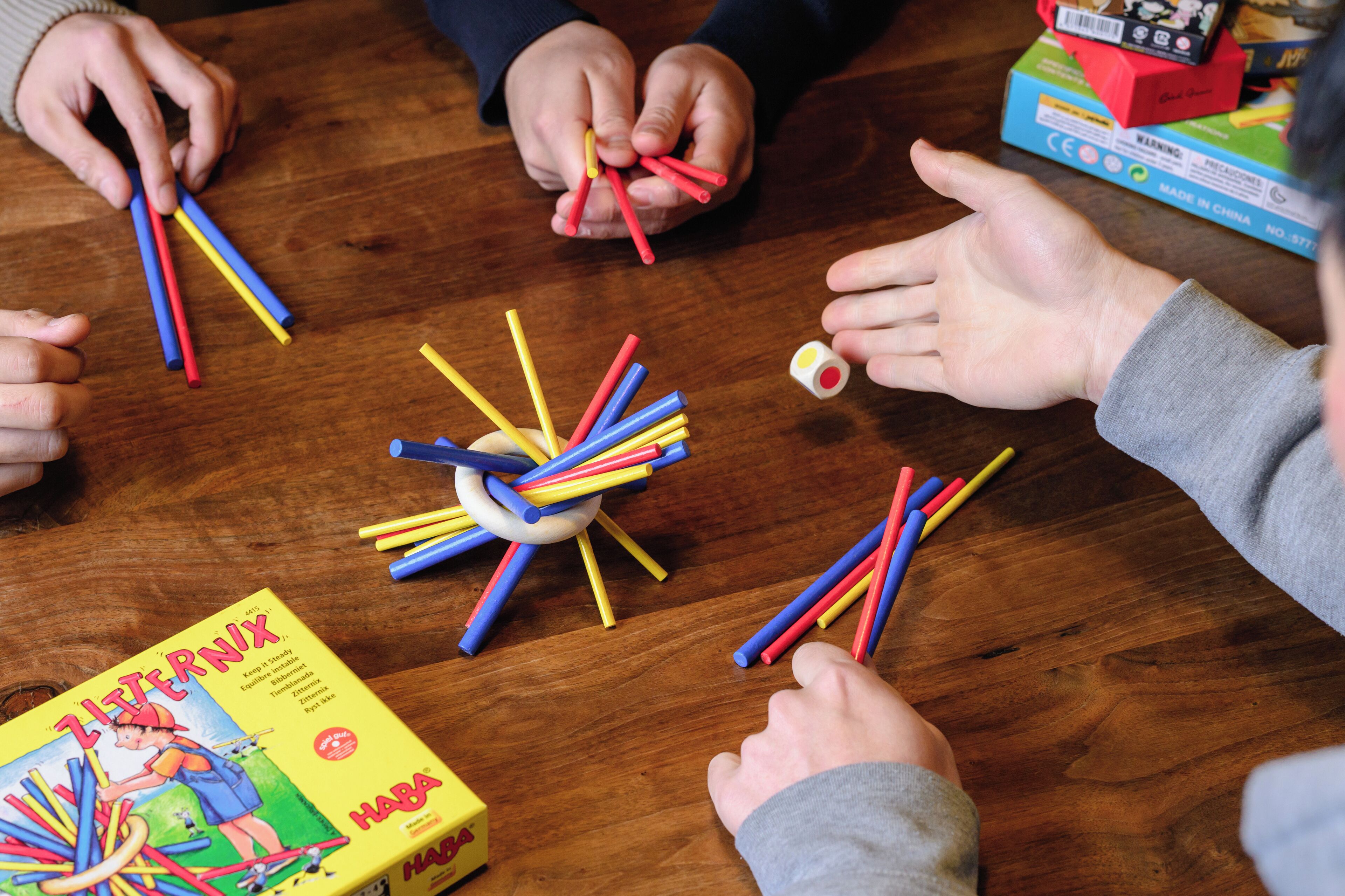 Un grupo de personas jugando con palos de colores sobre una mesa de madera.