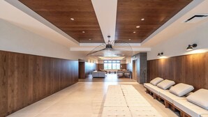 Un espacio interior amplio con techo alto, paneles de madera y una zona de estar central con bancos acolchados.