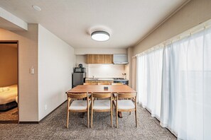 Quarto de hotel compacto com uma mesa de jantar de madeira e cadeiras, uma cozinha compacta e uma cama.