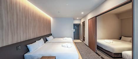 Ein Hotelzimmer mit zwei Betten, einer hölzernen Bank und einem kleinen Tisch.