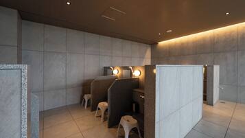 A modern restroom with individual cubicles, each equipped with a mirror and a light.