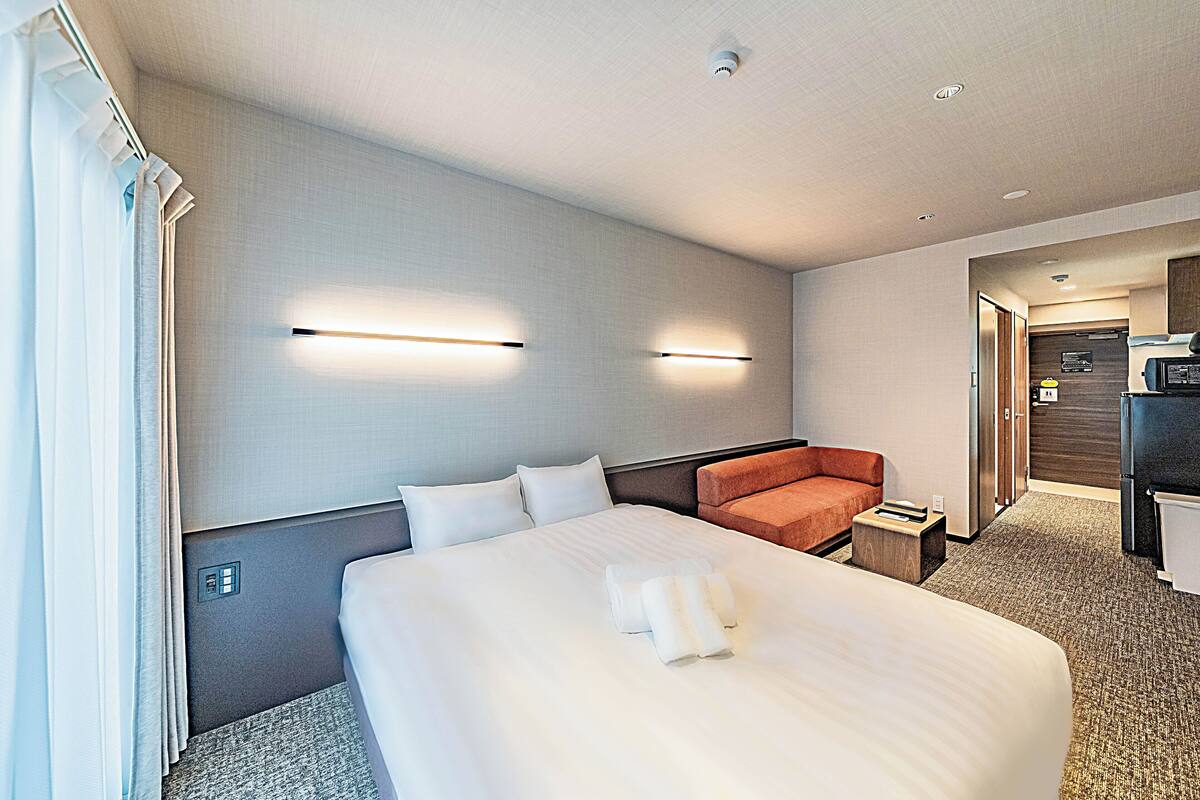 Ein Hotelzimmer mit einem großen Bett, einer kleinen Couch und einer Küchenzeile.