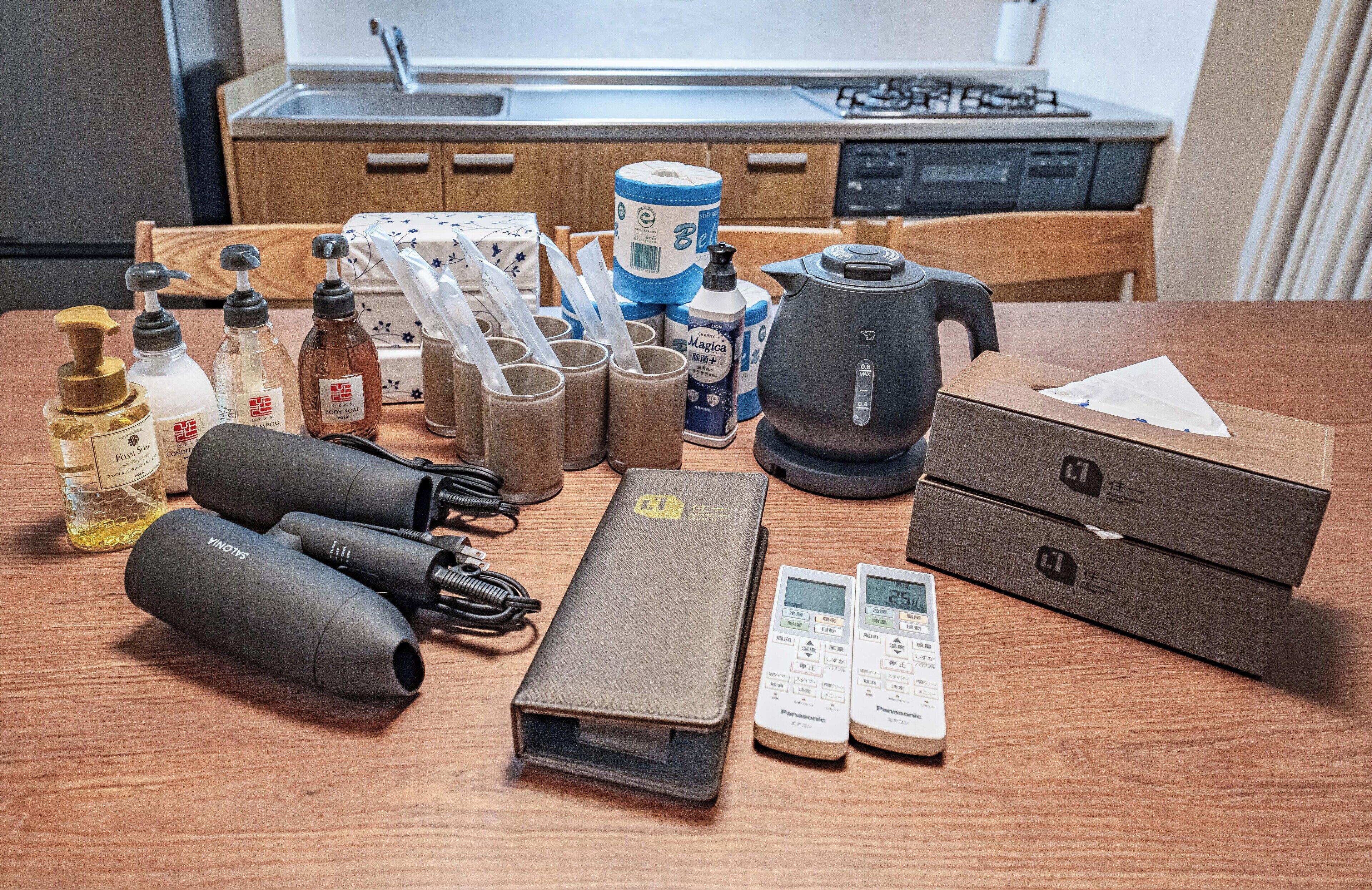Een keukenhoek met diverse apparaten en items, waaronder een waterkoker, een koffiezetapparaat en een Panasonic magnetron. Er staan ook verschillende flessen en containers, mogelijk voor kruiden of drankjes.