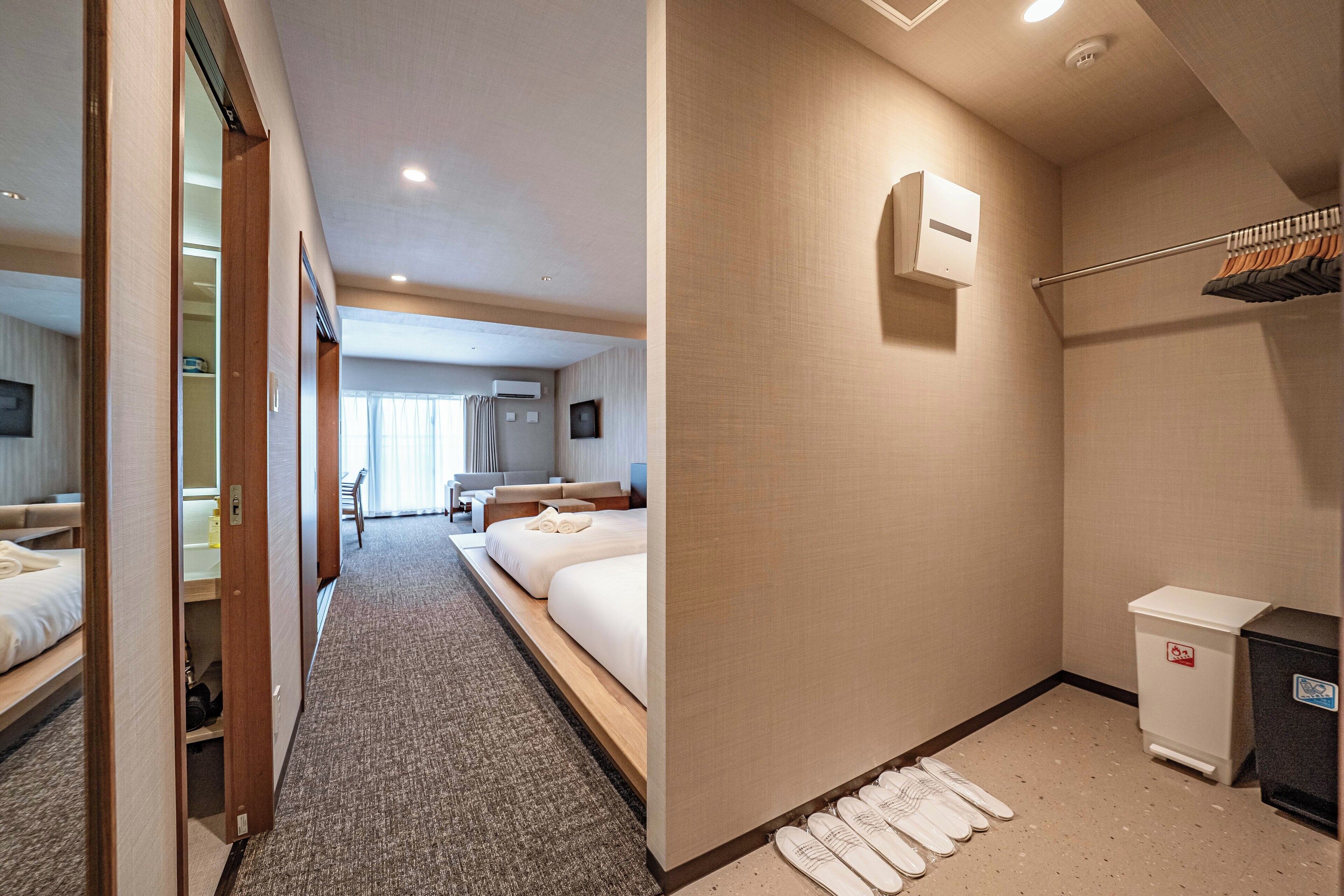 A hotel room with a bed, a desk, a chair, a wardrobe, and a bathroom with a shower and a toilet.