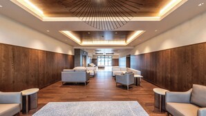 Un vestíbulo amplio con una zona de estar central, paneles de madera en las paredes y un diseño de techo moderno.