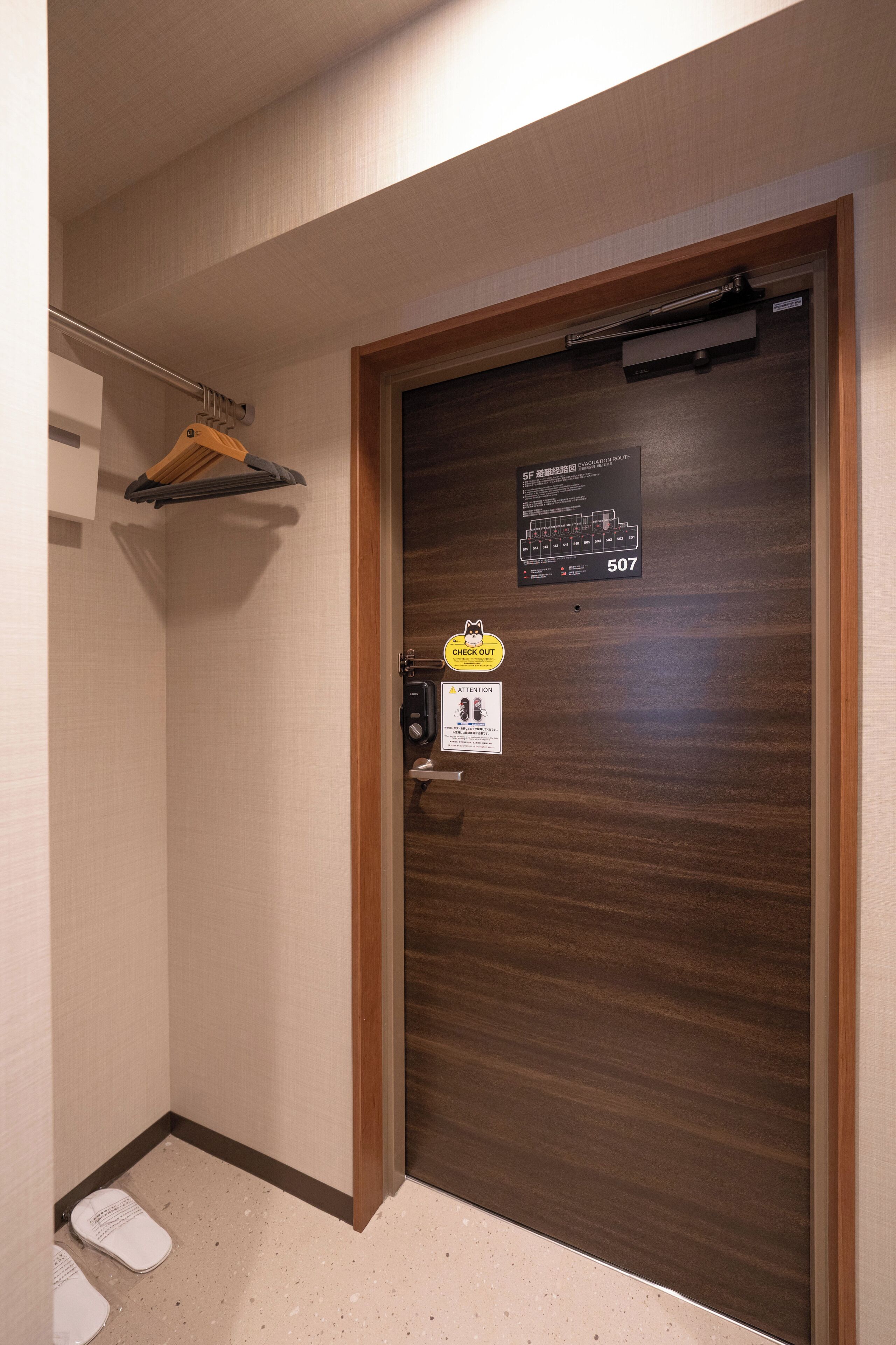 Une chambre d’hôtel avec une porte en bois, un porte-serviettes et une pancarte indiquant le numéro de chambre : 507.