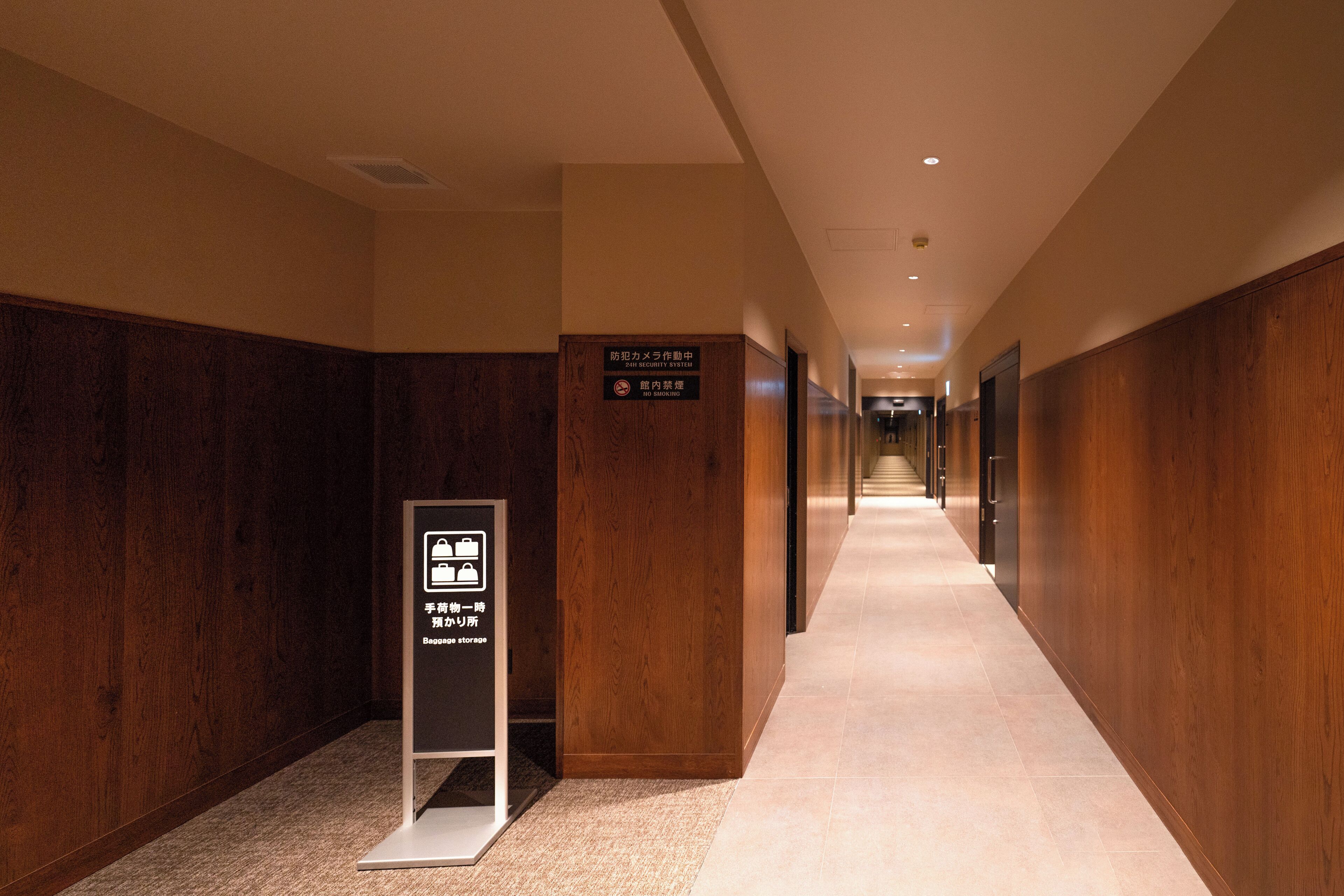 Un couloir d’hôtel avec des lambris en bois, un panneau indiquant le poste de sécurité et un panneau indiquant un local de stockage.