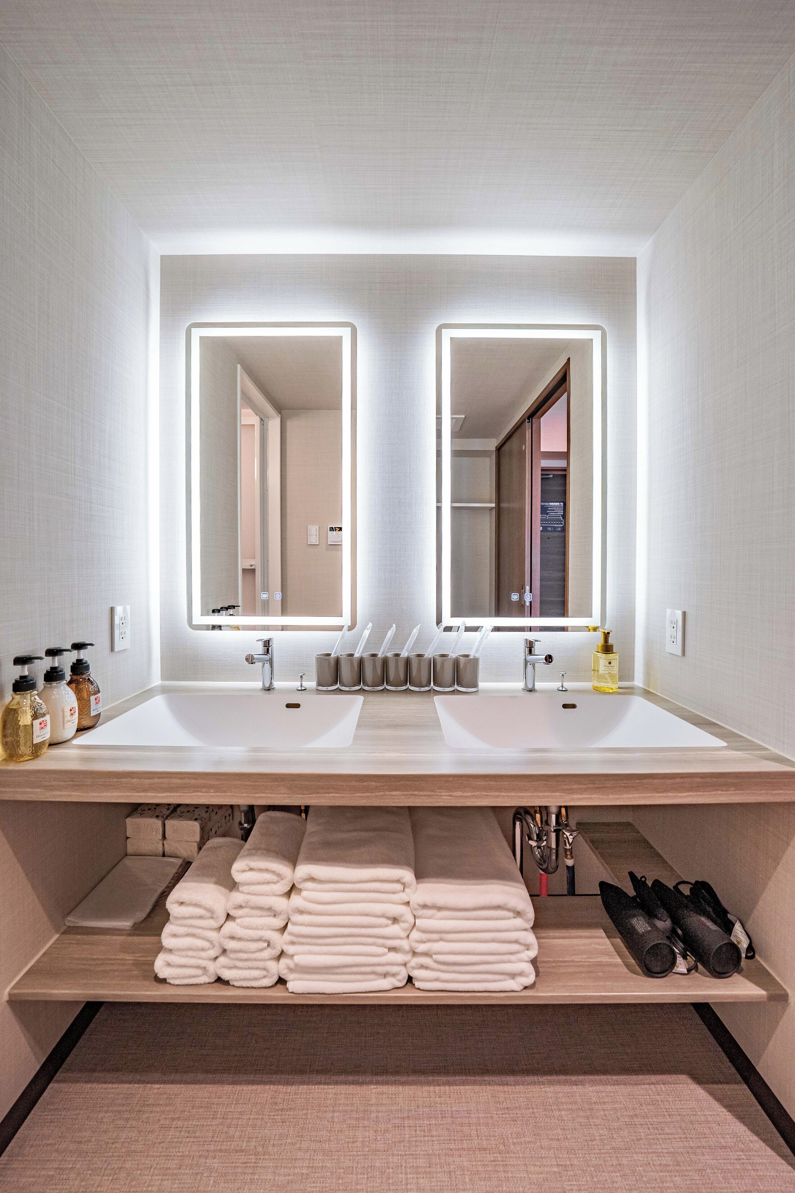 Un baño moderno con un espejo grande, dos lavamanos y un perchero para toallas.