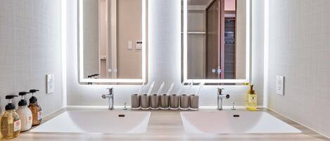 Un baño moderno con un espejo grande, dos lavamanos y un perchero para toallas.