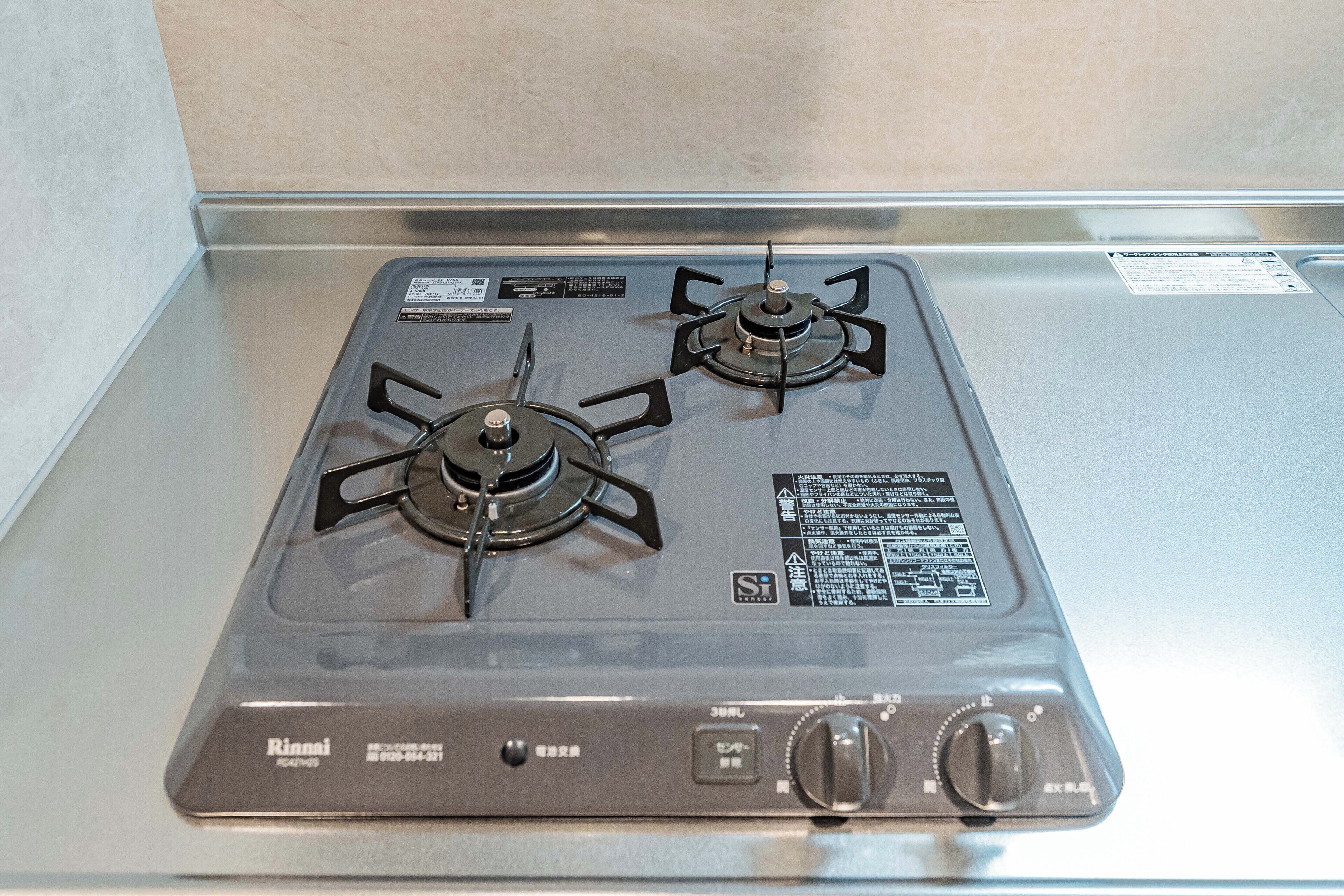 A gas stove with two burners and a control panel.