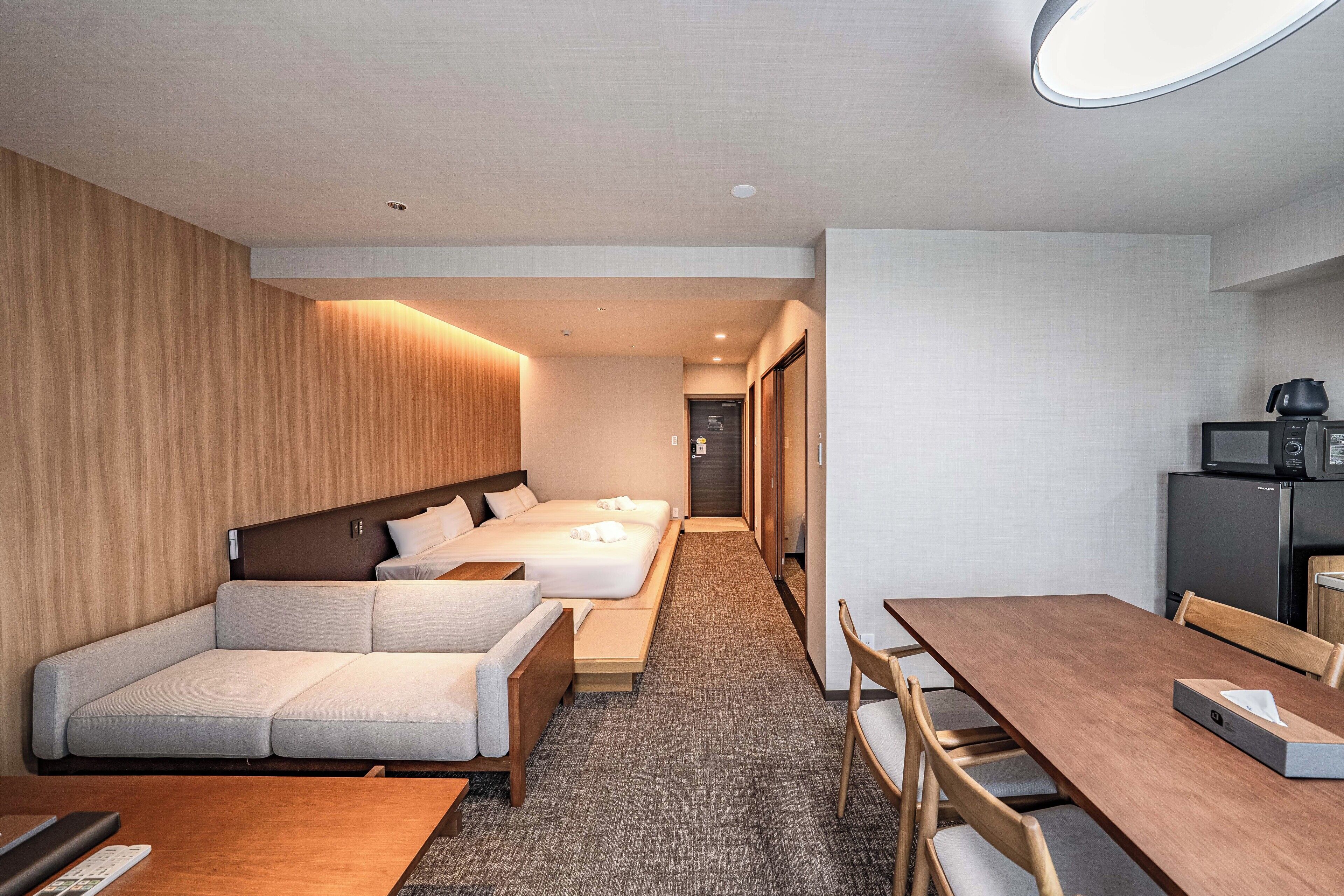 Une chambre d’hôtel avec un canapé, deux lits, une table à manger et un coin cuisine.