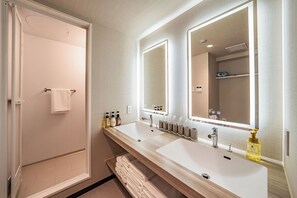 Uma casa de banho moderna com duas pias, um espelho grande e um chuveiro.