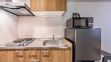 Una cocina moderna con un refrigerador de acero inoxidable, un microondas, una estufa a gas y armarios de madera.