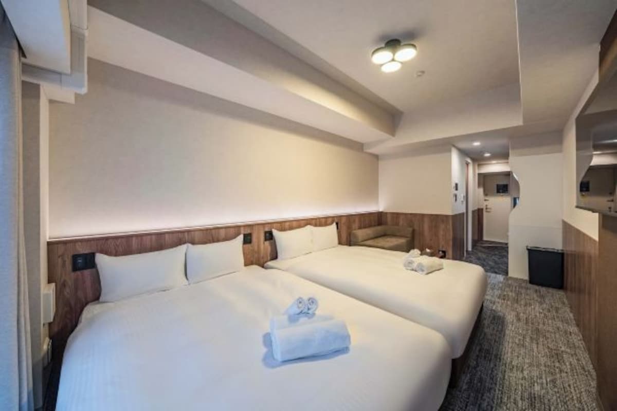 Ein Hotelzimmer mit zwei Betten, einem Holzkopfstück und einem Teppichboden.