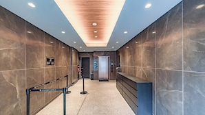 A modern hotel lobby with a marble floor, a reception desk, and an elevator. - Apartment Hotel 11 Nippombashi (Osaka)