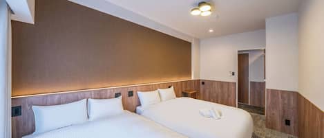 Habitación de hotel con dos camas, cabecero de madera, suelo alfombrado y lámpara en el techo.