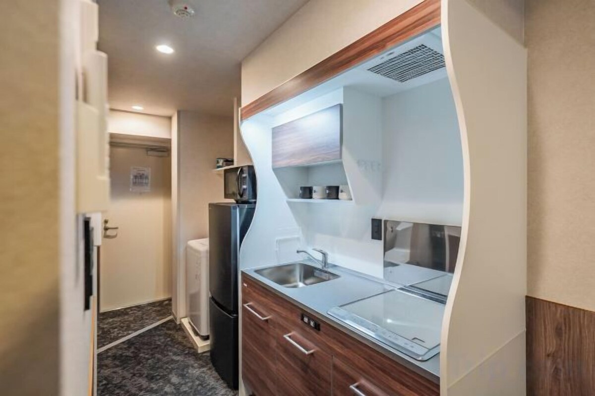 A compact kitchen with a refrigerator, microwave, and a sink.