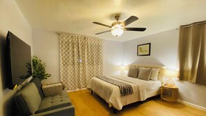 A bedroom with a bed, a chair, a ceiling fan, and a TV. - Spacious 5-bedroom Wheelchair Accessible House in Pittsburgh (Pittsburgh)
