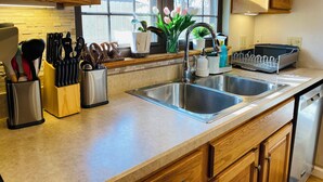 A kitchen with wooden cabinets, stainless steel sinks, and a window with a view of the outside. - Spacious 5-bedroom Wheelchair Accessible House in Pittsburgh (Pittsburgh)