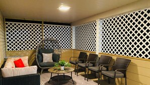 A covered outdoor seating area with wicker furniture, a cushioned chair, and a patterned rug. - Spacious 5-bedroom Wheelchair Accessible House in Pittsburgh (Pittsburgh)